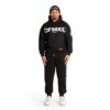 Full-body shot of a man in a black CFMEU NSW hoodie, black joggers, white sneakers, and a black beanie, standing against a white background.
